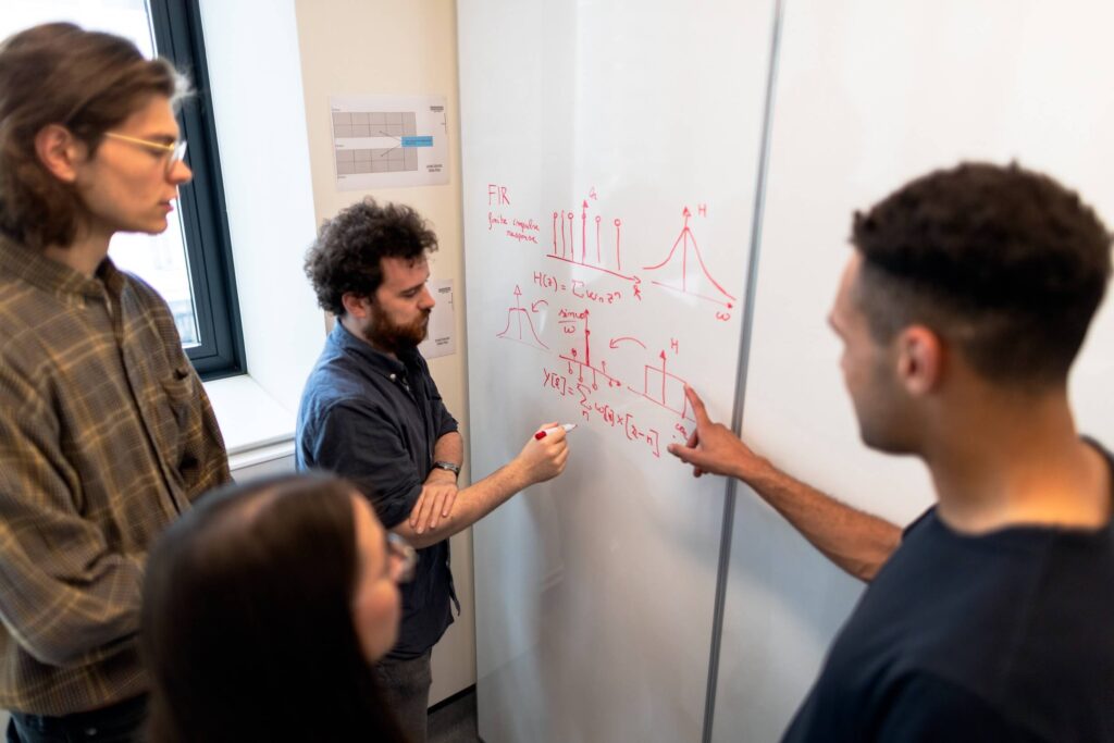 a group of engineers learning at a whiteboard